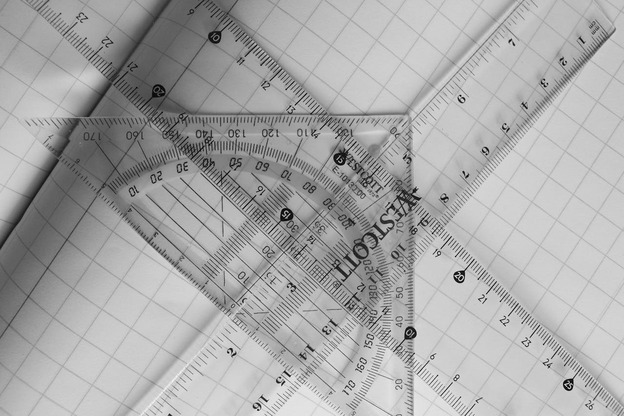 A black and white photo of geometric rulers arranged on graph paper, emphasizing precision and design.